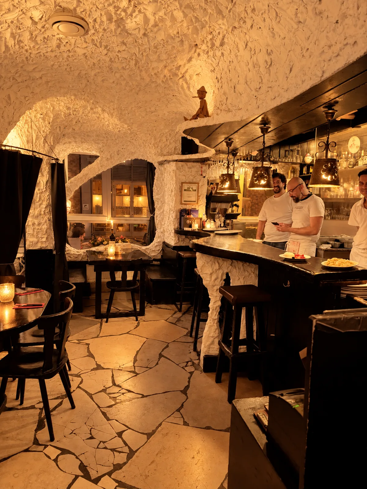 Theke unter der weißen Stuckdecke, das Team der Pizzeria Pinocchio bei der Arbeit